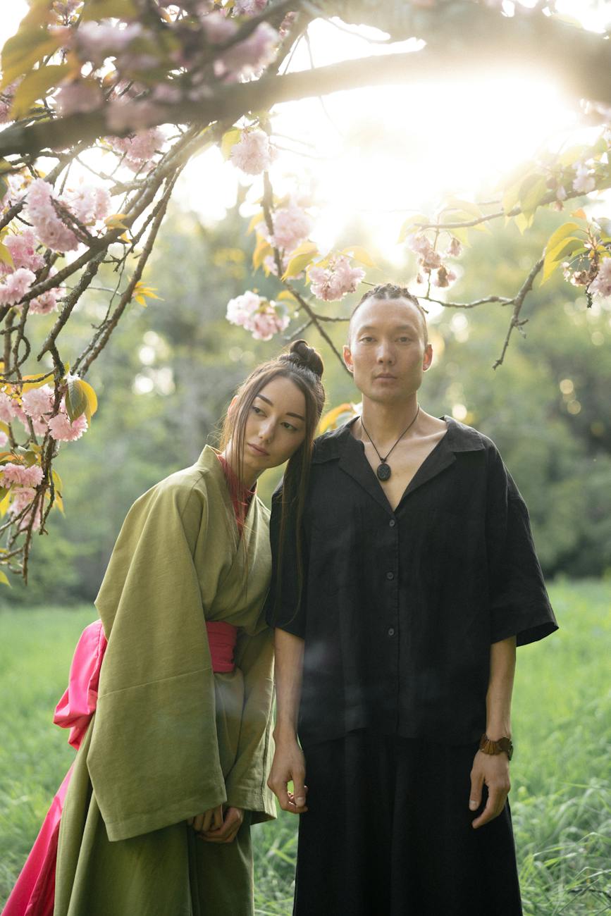 man and woman in their traditional outfit standing under a cherry blossom tree